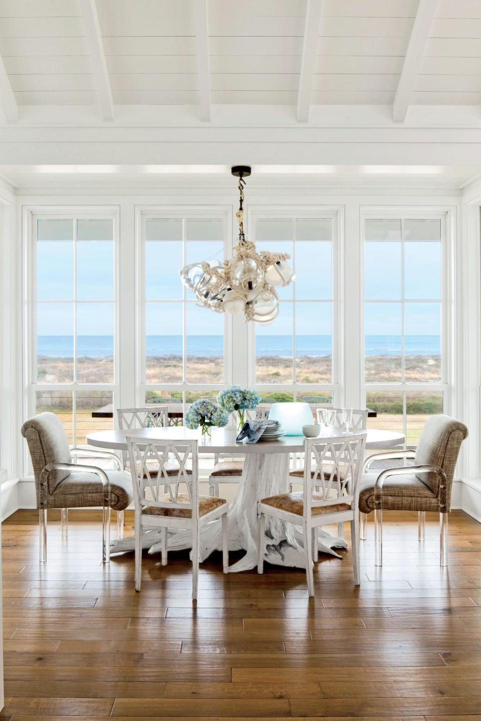 <p>A low-profile table, armless chairs with clean lines, and a glass-float chandelier keep all eyes on the view, while sturdy upholstered end chairs with acrylic arms add gravitas to the space.</p> <p><strong>Idea Spotlight</strong></p> <p>Bring the outside in by choosing pieces that highlight the natural landscape through their color or form, like this driftwood-inspired table. </p>