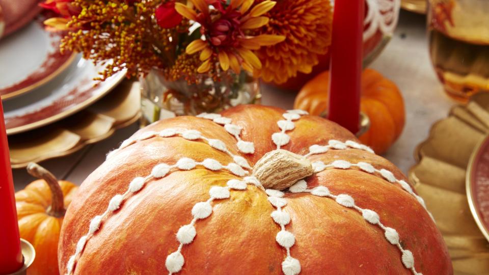 orange heirloom pumpkin decorated with sewing trim on a thanksgiving table