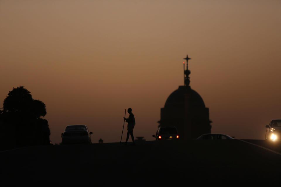 Mahesh Chaturvedi, who dresses up like Mahatma Gandhi, is silhouetted against the Rashtrapati Bhavan presidential palace in New Delhi