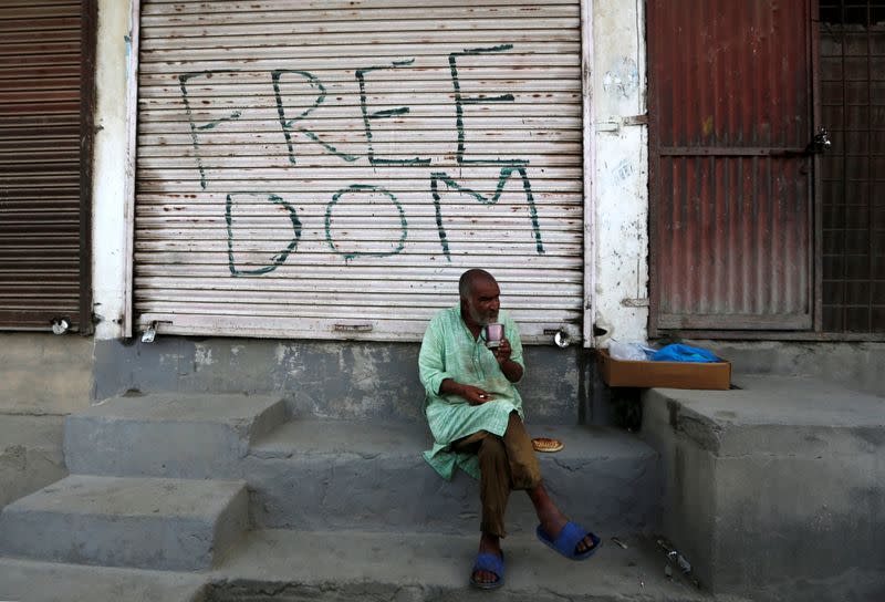 Kashmiri man drinks tea in front of a closed shop in Anchar neighbourhood in Srinagar