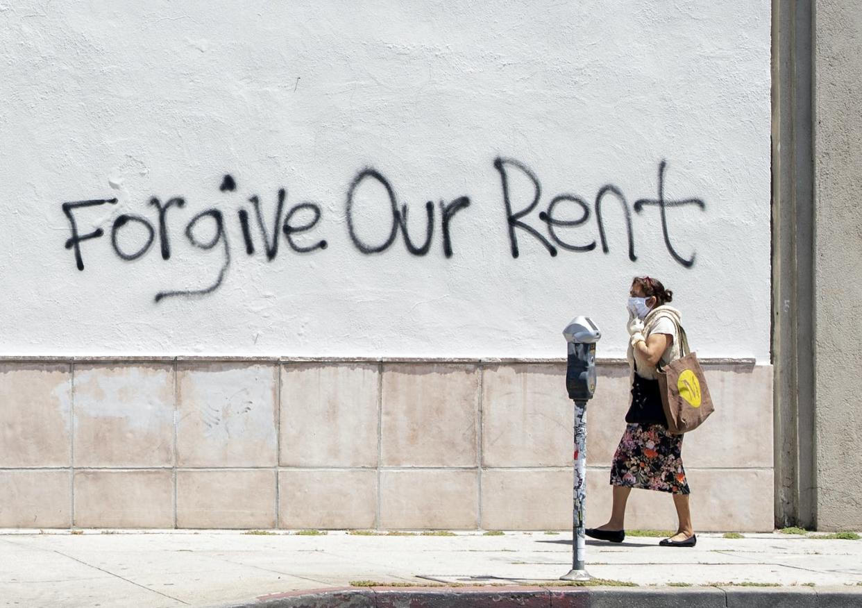 <span class="caption">Eviction moratoriums have already begun to expire. </span> <span class="attribution"><a class="link " href="https://www.gettyimages.com/detail/news-photo/woman-wearing-a-mask-walks-past-a-wall-bearing-a-graffiti-news-photo/1211479742" rel="nofollow noopener" target="_blank" data-ylk="slk:Valerie Macon/AFP via Getty Images;elm:context_link;itc:0;sec:content-canvas">Valerie Macon/AFP via Getty Images</a></span>