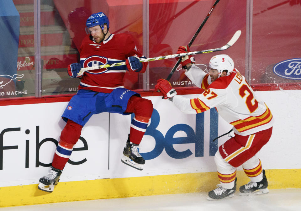 Montreal Canadiens' Brett Kulak avoids a hit from Calgary Flames' Josh Leivo during the third period of an NHL hockey game Friday, April 16, 2021, in Montreal. (Paul Chiasson/The Canadian Press via AP)