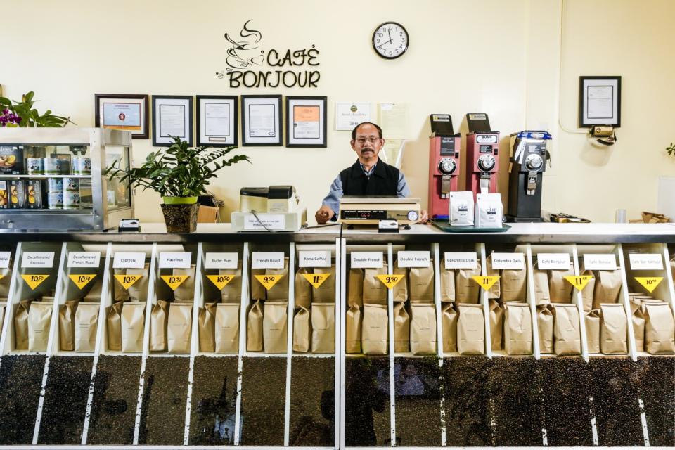 A man stands behind the counter at a coffee shop.