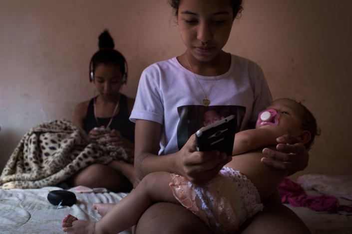 Nayane and her twin Nayara (in the back) send messages on their phones in their mother’s house in Parque Uniao, a shantytown in Rio de Janeiro, Brazil in August 2016. “A 30-year old single woman with no children is not normal- A man is?- Yes, it is normal in man,” says Nayara. For her, a woman, regardless of her schooling , “must marry and become a mother”, because the opposite is not natural. (Photo: Rafael Fabrés)