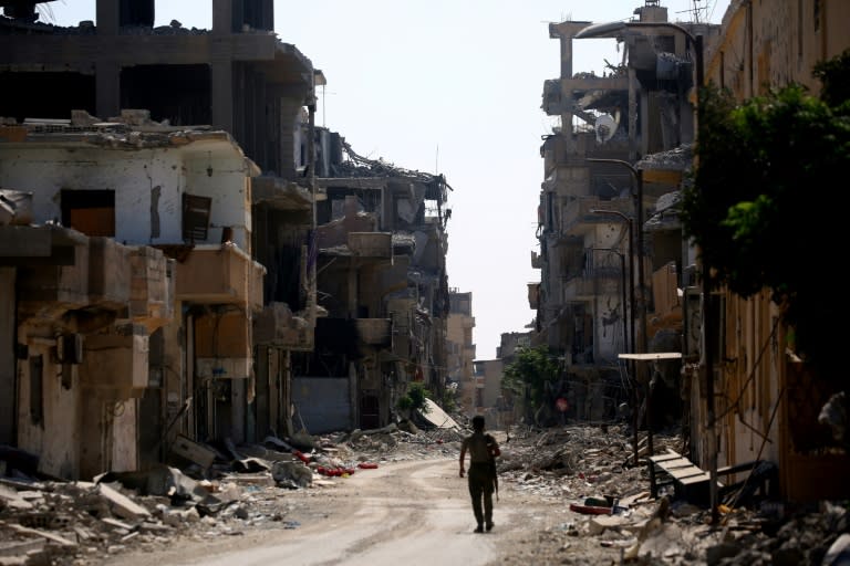 A member of the US-backed Syrian Democratic Forces walks among the ruins of Raqa on September 21, 2017