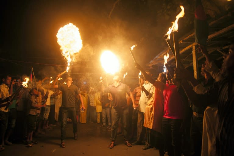 Former Indian enclave residents look on during a fire eating performance at Dasiarchhara, Kurigram in Bangladesh on August 1, 2015