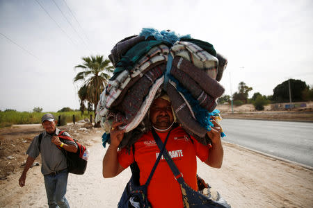 A migrant, part of a caravan of thousands traveling from Central America en route to the United States, carries blankets on his head while moving to a new shelter in Mexicali, Mexico November 19, 2018. REUTERS/Kim Kyung-Hoon