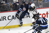 Winnipeg Jets' Andrew Copp (9) and Arizona Coyotes' Shayne Gostisbehere (14) battle for the puck during the first period of NHL hockey game action in Winnipeg, Manitoba, Monday, Nov. 29, 2021. (Fred Greenslade/The Canadian Press via AP)