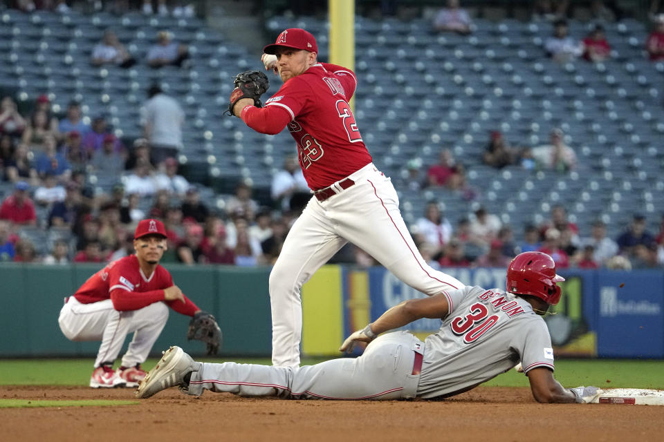 Cincinnati Reds' Will Benson, right, dives back to second safely as Los Angeles Angels second baseman Brandon Drury, center, throws out Tyler Stephenson at first while shortstop Andrew Velazquez watches during the second inning of a baseball game Tuesday, Aug. 22, 2023, in Anaheim, Calif. (AP Photo/Mark J. Terrill)