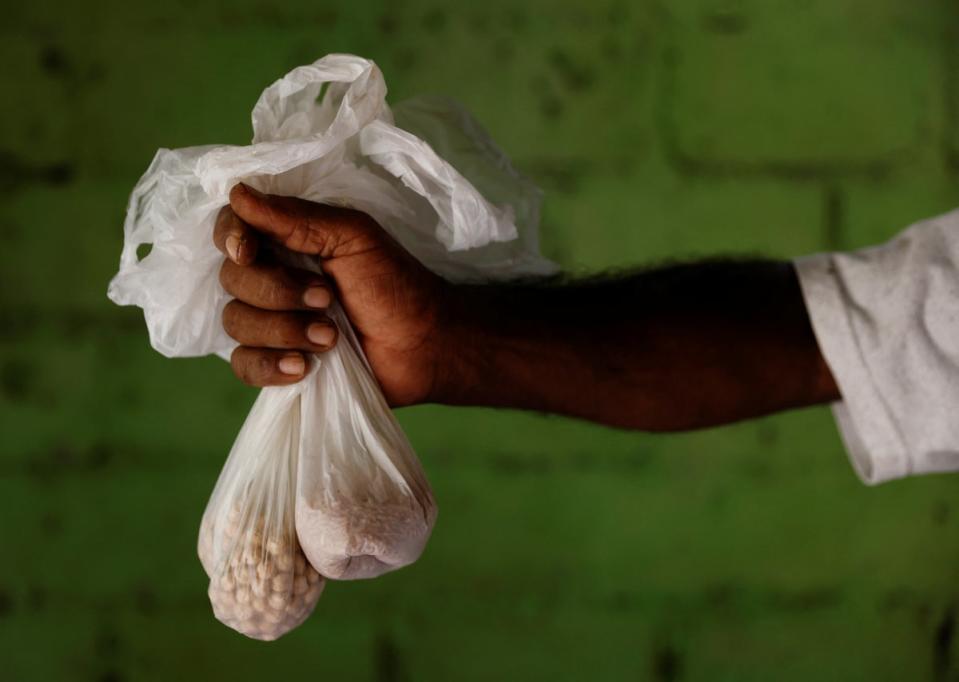Nihal with two small plastic bags of chickpeas and rice, the only grain his family currently has (Reuters)