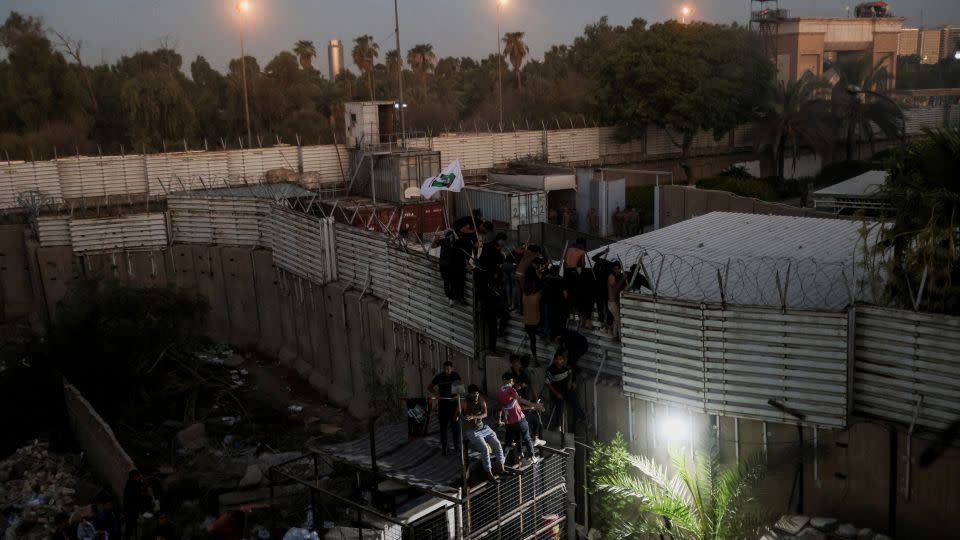 Protesters climb a fence as they gather near the Swedish embassy in Baghdad on Thursday.  - Ahmed Saad/Reuters