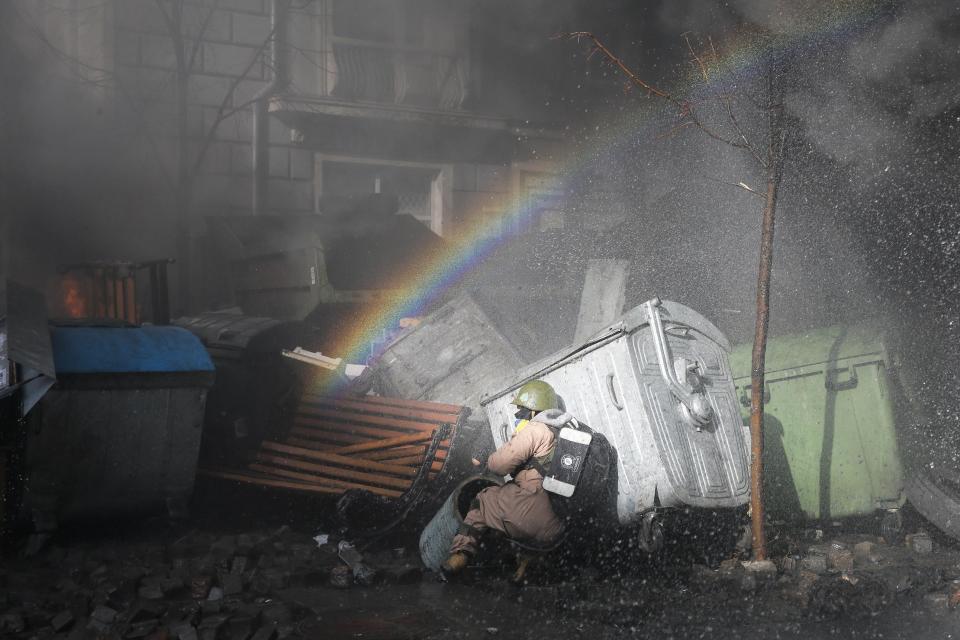 An anti-government protester finds cover during clashes with riot police outside Ukraine's parliament in Kiev, Ukraine, Tuesday, Feb. 18, 2014. Thousands of angry anti-government protesters clashed with police in a new eruption of violence following new maneuvering by Russia and the European Union to gain influence over this former Soviet republic. (AP Photo/Efrem Lukatsky)