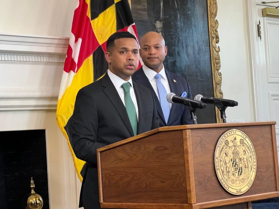 Paul Monteiro, the governor's nominee to be the state's first secretary of service, speaks at the lectern during the announcement of his nomination on April 3, 2023. Democratic Gov. Wes Moore stands behind Monteiro, a native Marylander.