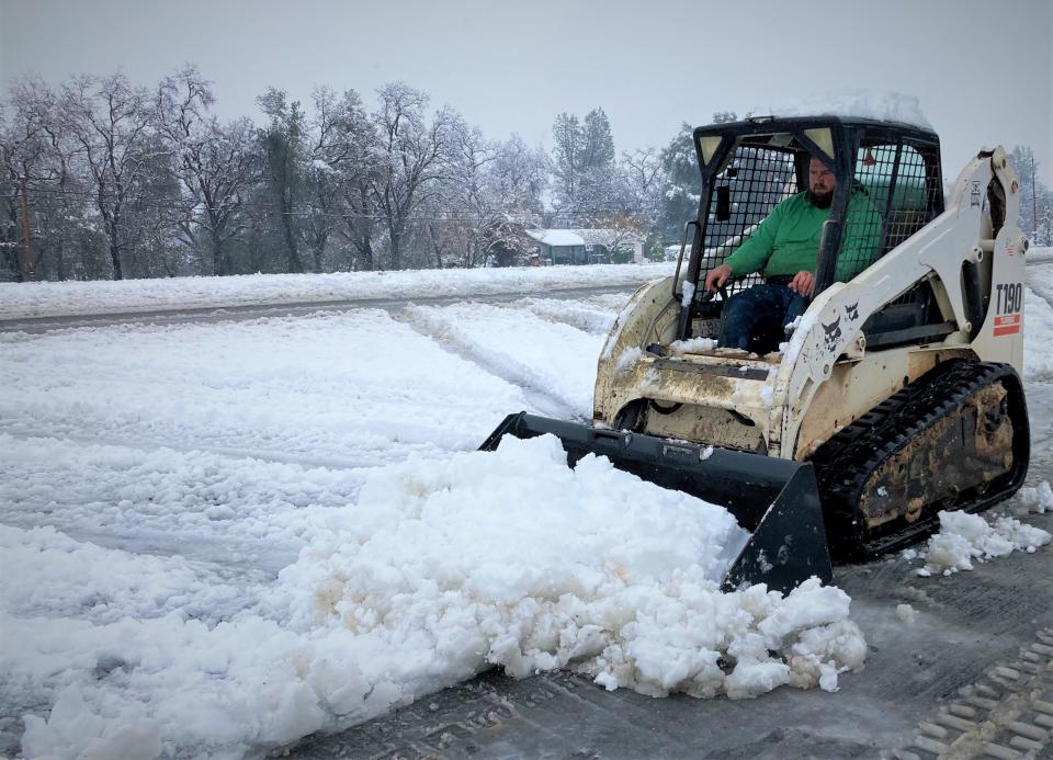 Brandon Ray clears snow off a driveway for his neighbors south of Redding on Friday.