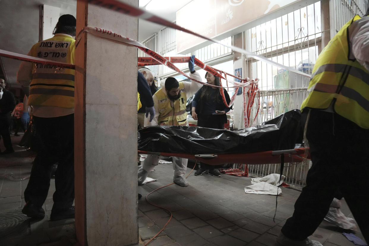 A body is removed from the site where a gunman opened fire in Bnei Brak, Israel, Tuesday, March 29, 2022. (AP Photo/Oded Balilty)