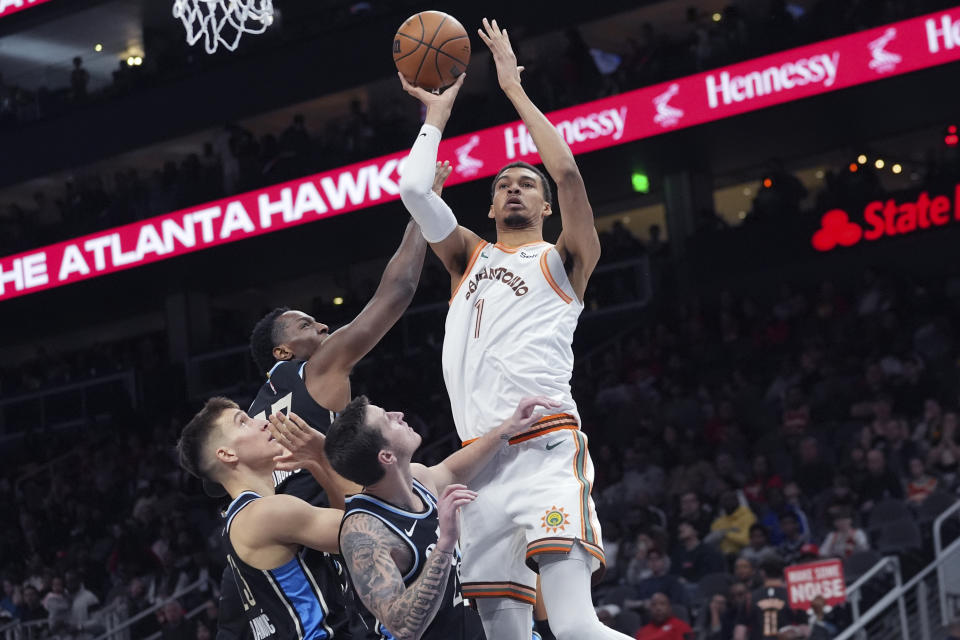 San Antonio Spurs center Victor Wembanyama (1) is defended by Atlanta Hawks' Onyeka Okongwu (17), Bogdan Bogdanovic and Garrison Mathews (25) as he shoots during the first half of an NBA basketball game Monday, Jan. 15, 2024, in Atlanta. (AP Photo/John Bazemore)