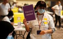 A volunteer holds a sign requesting more vaccines at a coronavirus disease (COVID-19) pop-up vaccination centre at Wembley Stadium in London