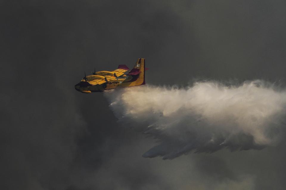 A Canadair aircraft drops water over a wildfire in Vati village, on the Aegean Sea island of Rhodes, southeastern Greece, on Tuesday, July 25, 2023. A third successive heat wave in Greece pushed temperatures back above 40 degrees Celsius (104 degrees Fahrenheit) across parts of the country Tuesday following more nighttime evacuations from fires that have raged out of control for days. (AP Photo/Petros Giannakouris)