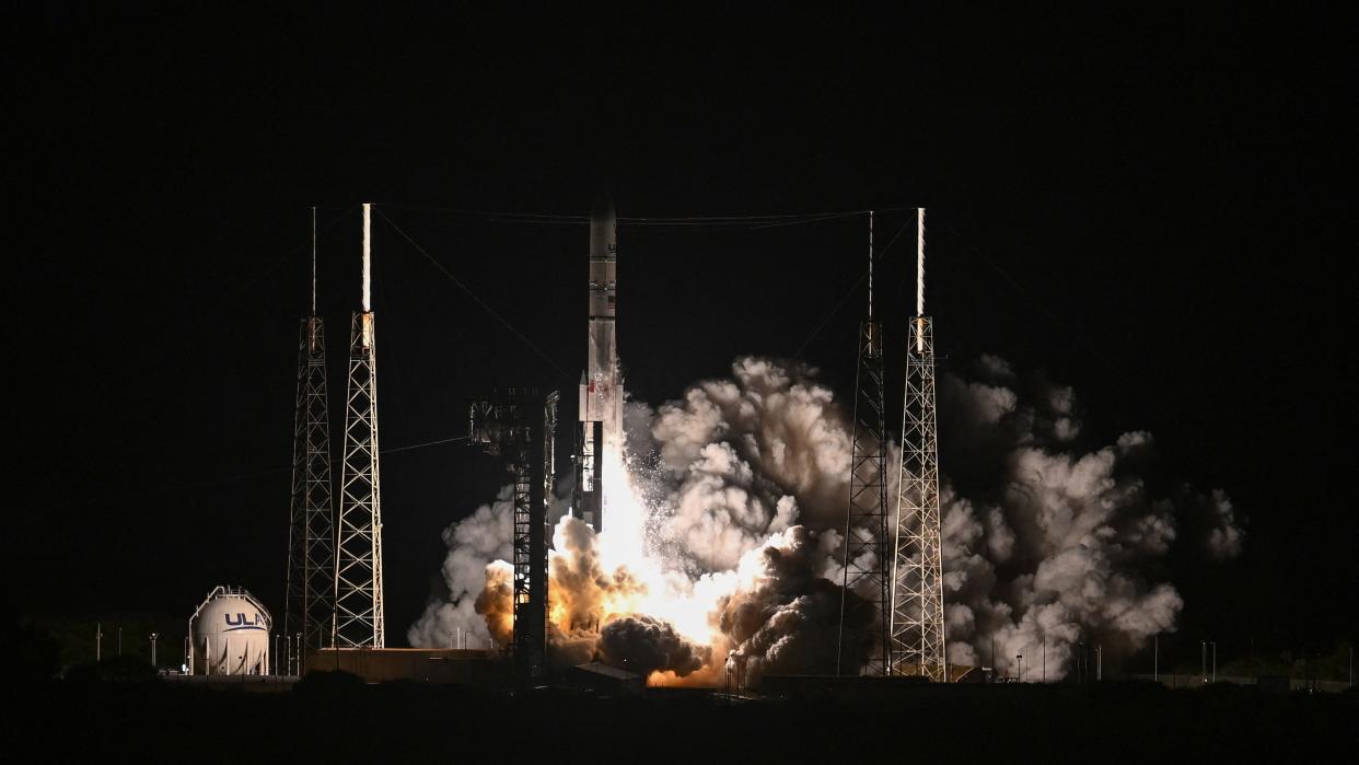  A white rocket launches into a dark night sky. 