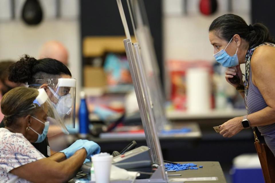 A voter shows identification to a Harris county election clerk before voting in Houston, Texas, on 14 July 2020.