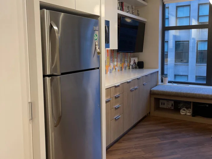 Silver refrigerator and white cabinets in front of kitchen counter and wood floor