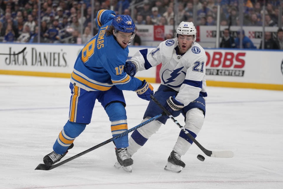 St. Louis Blues' Robert Thomas (18) and Tampa Bay Lightning's Brayden Point (21) battle for a loose puck during the second period of an NHL hockey game Saturday, Jan. 14, 2023, in St. Louis. (AP Photo/Jeff Roberson)