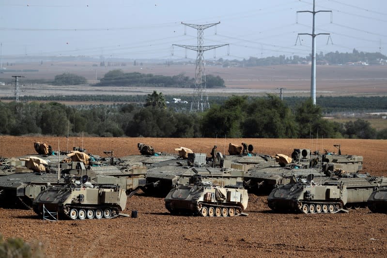 Israeli soldiers stand atop armoured personnel carriers in a staging area near the border with Gaza, in southern Israel