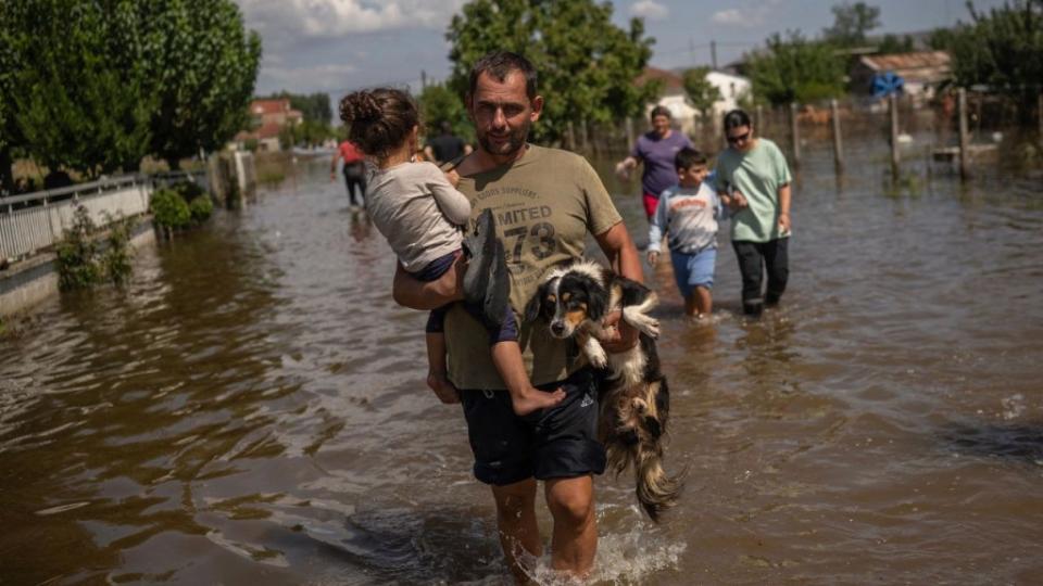 Un hombre carga a una niña y a un perro en el pueblo inundado de Palamas, en el centro de Grecia, el 8 de septiembre de 2023. (Crédito: Angelos Tzortzinis/AFP/Getty Images)