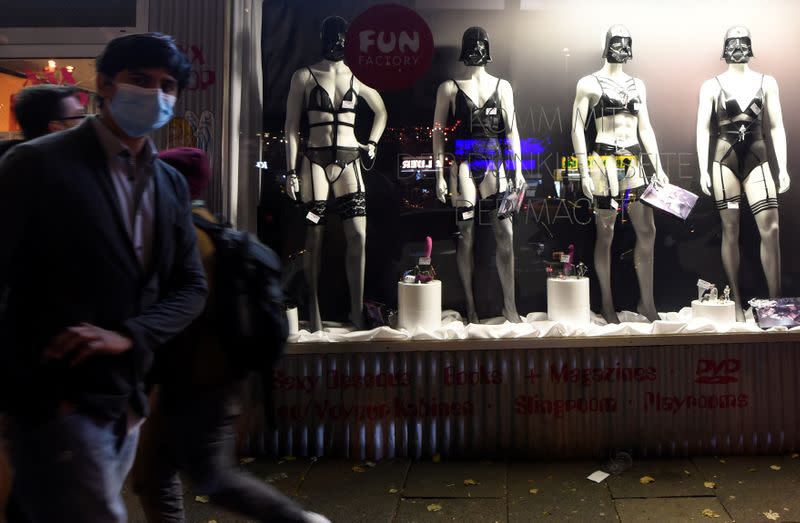 People walk in front of a shop window at famous red-light-district Reeperbahn during the spread of the coronavirus disease (COVID-19), in Hamburg