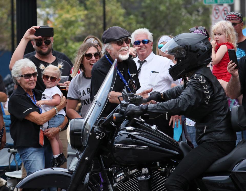 Willie G. Davidson (center) greets riders as they pass by during the motorcycle parade for the Harley-Davidson 115th anniversary celebration in Milwaukee on Sept. 2, 2018.. His daughter, Kayley Grewe (center left), looks on as his wife, Nancy, holds their granddaughter, Penelope Grewe.