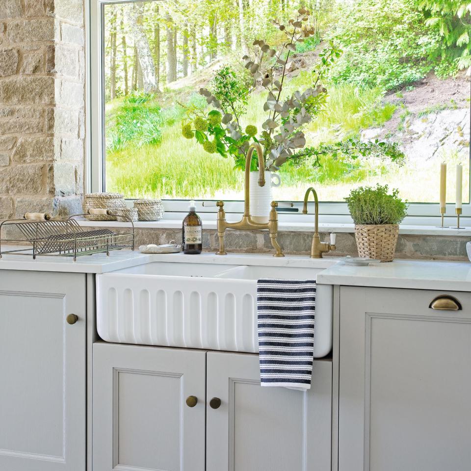 White kitchen sink with neutral cabinets under a window