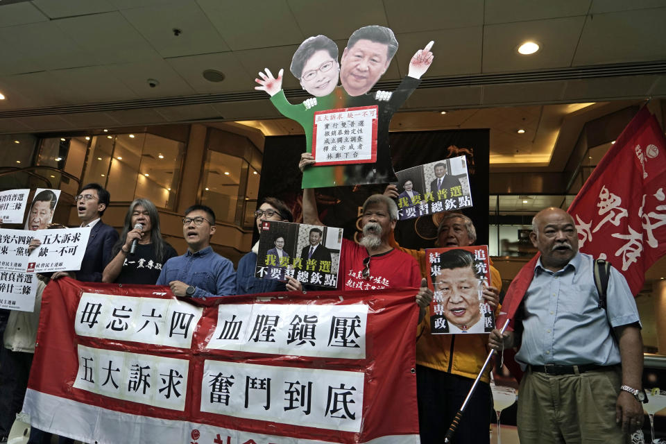 Pro-democracy activists hold up placards of Chinese President Xi Jinping and Hong Kong Chief Executive Carrie Lam, at a ferry terminal in Hong Kong, Wednesday, Dec. 18, 2019. A ferry company barred a Hong Kong activist "Long Hair", whose real name is Leung Kwok-hung, from boarding a boat Wednesday to Macao, where Chinese President Xi Jinping is slated to arrive for the 20th anniversary of Macau's return to China, The placards read "Five demands, not one less", "I want genuine universal suffrage", "Vindicate June 4th" and "Put an end to one-party Dictatorship". (AP Photo/Kin Cheung)