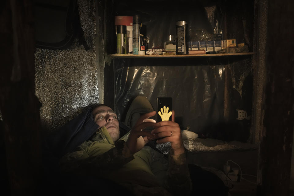 A Ukrainian serviceman lies in bed looking at a mobile phone at a front line position in the Luhansk area, eastern Ukraine, Friday, Jan. 28, 2022. High-stakes diplomacy continued on Friday in a bid to avert a war in Eastern Europe, the urgent efforts coming as 100,000 Russian troops are massed near Ukraine's border and the Biden administration worries that Russian President Vladimir Putin will mount some sort of invasion within weeks. (AP Photo/Vadim Ghirda)