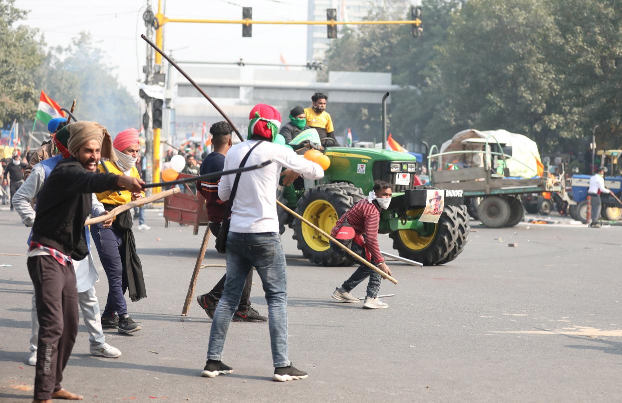 Farmers hold sticks as they confront police officers in Delhi (EPA)