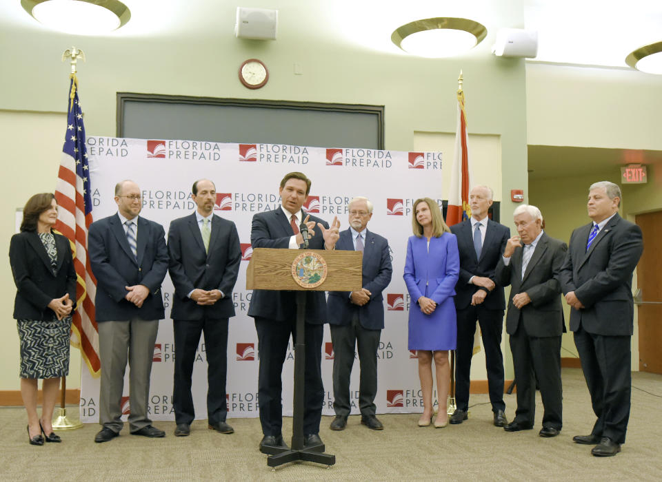 Florida Gov. Ron DeSantis, center, backed by others involved in the Florida state college system, announces that there would be refunds coming to families that have been paying into the Florida Prepaid tuition plan since 2008 and a reduction in the costs for new enrollments during a press conference in Jacksonville, Fla., Monday, Jan. 13, 2020. (Bob Self/The Florida Times-Union via AP)