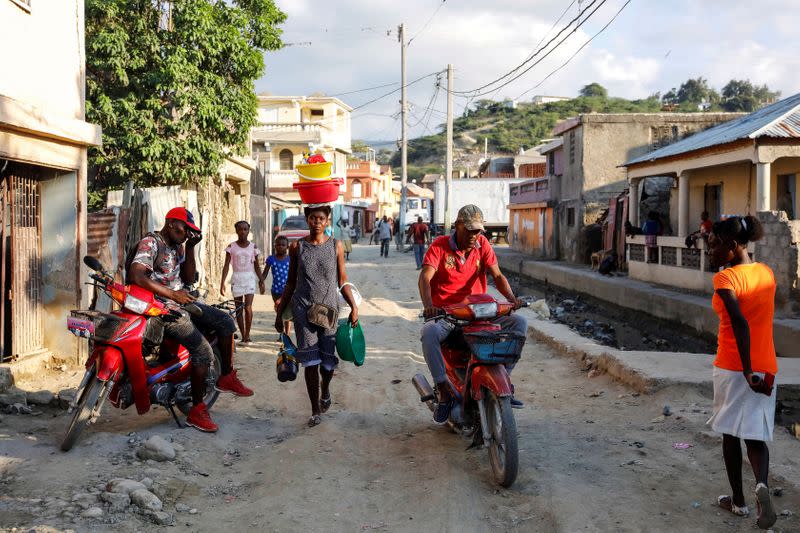 People are seen along a street in Port-de-Paix