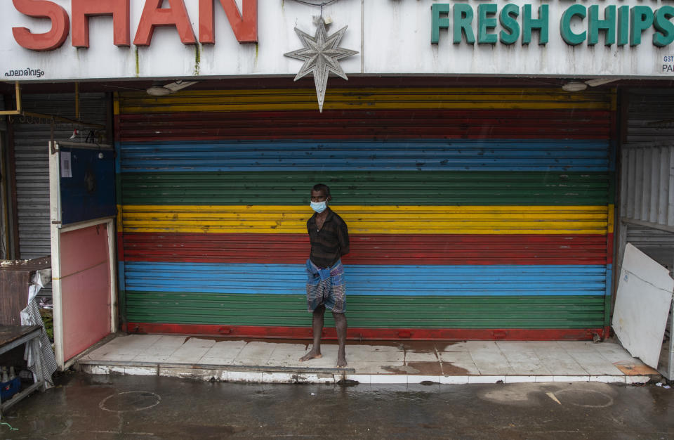 A man wearing a mask stands outside a closed shop during a nation-wide shutdown to protest against the contentious farm laws in Kochi, Kerala state, India, Monday, Sept.27, 2021. Shops remained shut and most vehicles stayed off the roads in this southern state where the ruling Left Democratic Front called for a total shutdown. (AP Photo/R S Iyer)