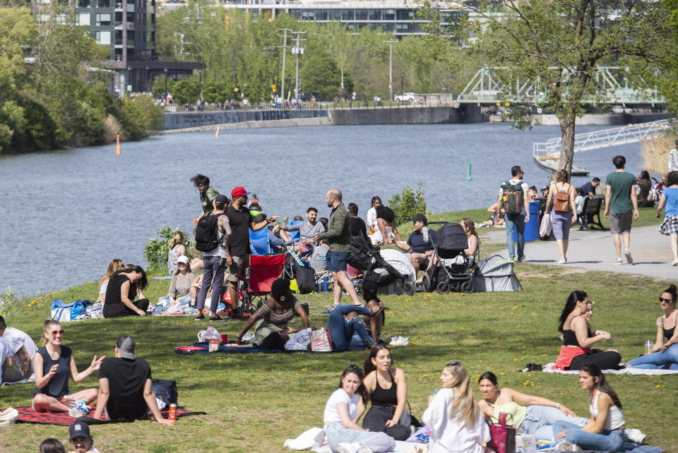 People gather next to the Lachine Canal on a warm spring day in Montreal, Saturday, May 15, 2021, as the COVID-19 pandemic continues in Canada and around the world. (Graham Hughes/The Canadian Press via AP)