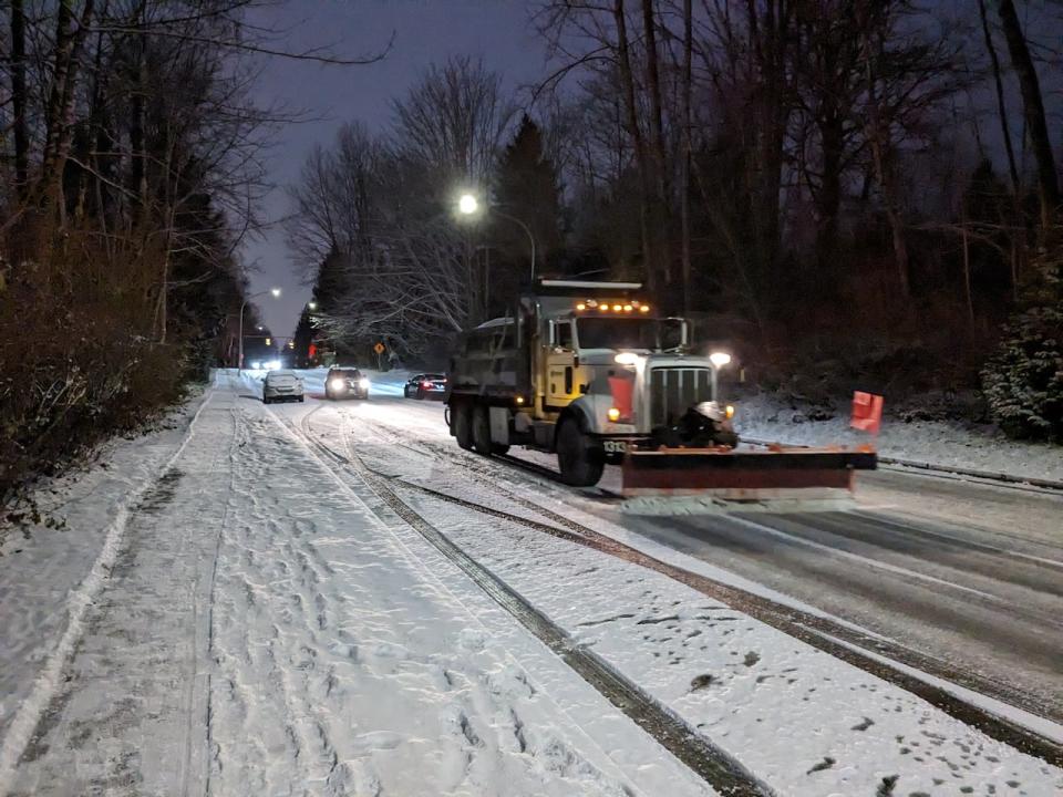 A snow plow clears and salts Forest Grove Drive in Burnaby, B.C., after snowfall on Jan. 11, 2024. 