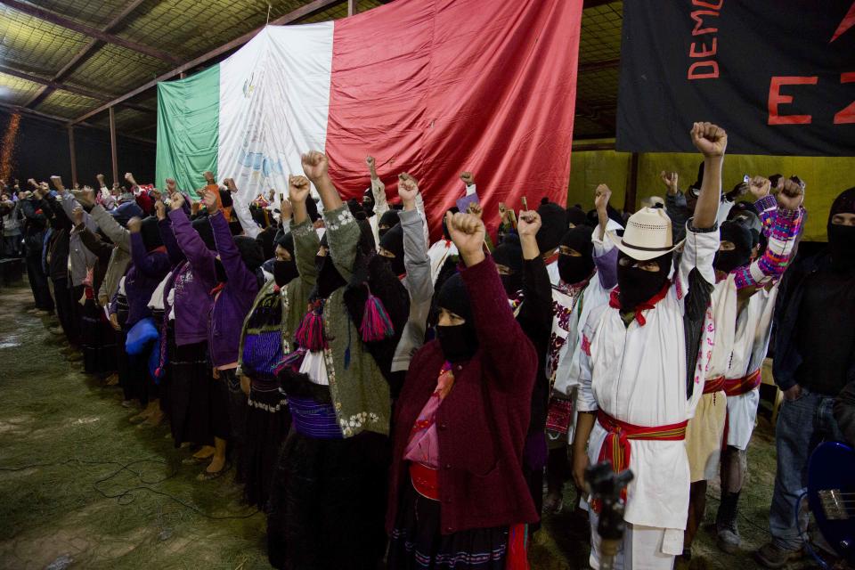 Masked members of the Zapatista National Liberation Army, EZLN, raise their fists during an event marking the 20th anniversary of the Zapatista uprising in the town of Oventic, Chiapas, Mexico, late Tuesday, Dec. 31, 2013. The revolt led Mexico to amend its constitution in 2001 to enshrine Indian rights, but the Zapatistas were enraged when lawmakers watered down the protections before approving them. (AP Photo/Eduardo Verdugo)