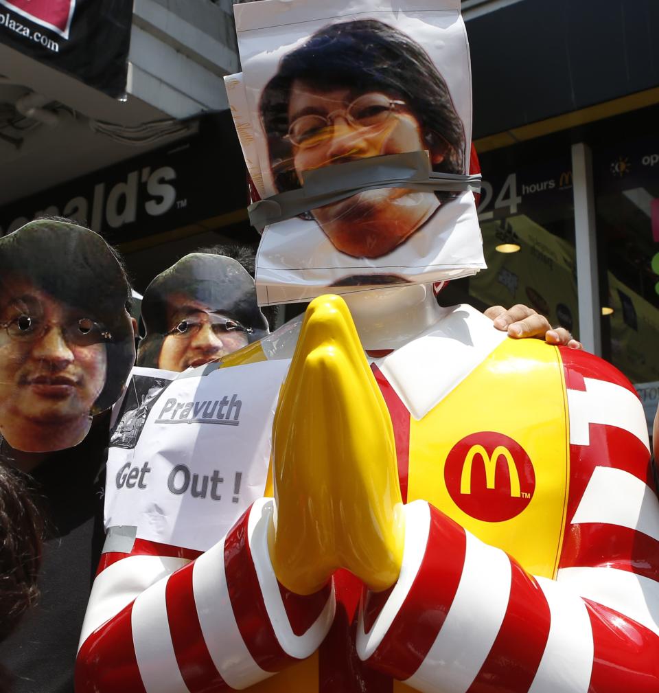 Protesters against military rule wear masks of Sombat Boonngamanong, an outspoken Thai journalist and supporter of the protest movement against military rule, next to a statue of Ronald McDonald during a rally at a shopping district in central Bangkok May 25, 2014. Thailand's military tightened its grip on power on Sunday as it moved to douse smouldering protests fuelled by social media and to rally commercial agencies and business to revitalise a battered economy. REUTERS/Erik De Castro (THAILAND - Tags: POLITICS CIVIL UNREST)