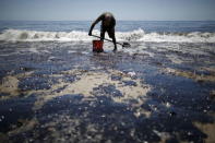 William McConnaughey, 56, who drove from San Diego to help shovel oil off the beach, stands in an oil slick in bare feet along the coast of Refugio State Beach in Goleta, May 20, 2015. REUTERS/Lucy Nicholson