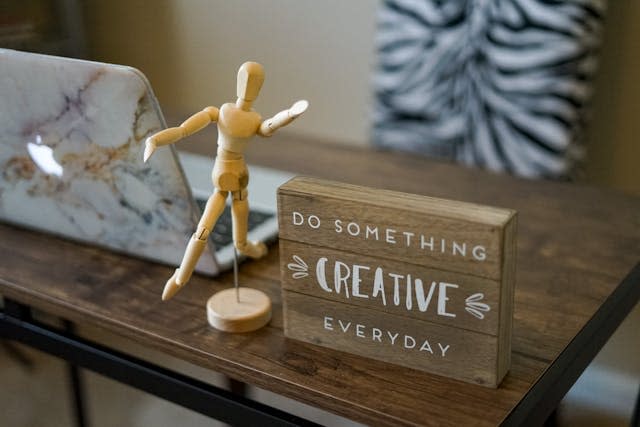 Desk plaque says "Do something creative everyday" with a human anatomy statue nearby