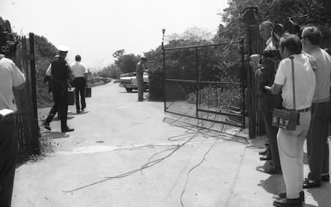 Police pass by newsmen as they go through the gate that leads to the house where a woman, identified as actress Sharon Tate, and four other persons were found shot to death  - Credit: Bettmann