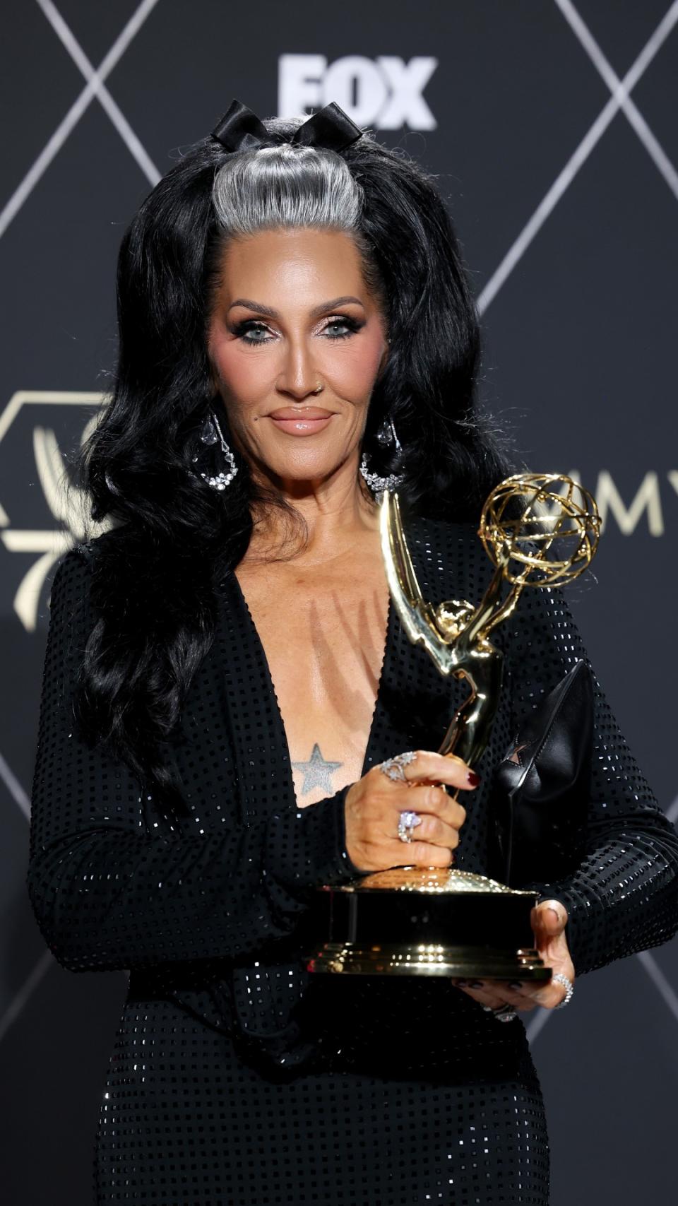 Michelle Visage posing with an Emmy award for RuPaul's Drag Race