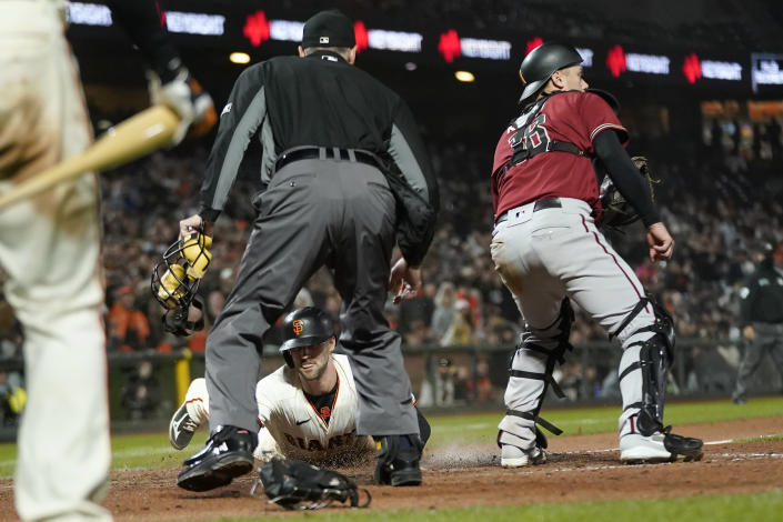 San Francisco Giants' Steven Duggar, bottom, slides into home to score against Arizona Diamondbacks catcher Carson Kelly, right, as home plate umpire Dan Iassogna watches during the seventh inning of a baseball game in San Francisco, Wednesday, Sept. 29, 2021. (AP Photo/Jeff Chiu)