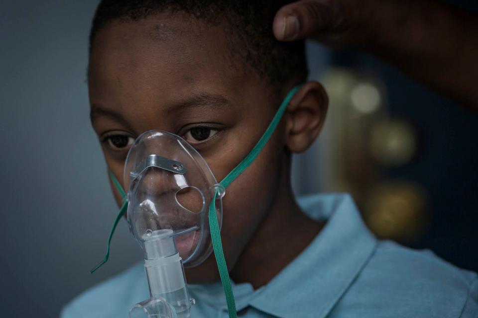 Thelma Freeman demonstrates how a nebulizer is worn on her grandson Jayceon in Pahokee.