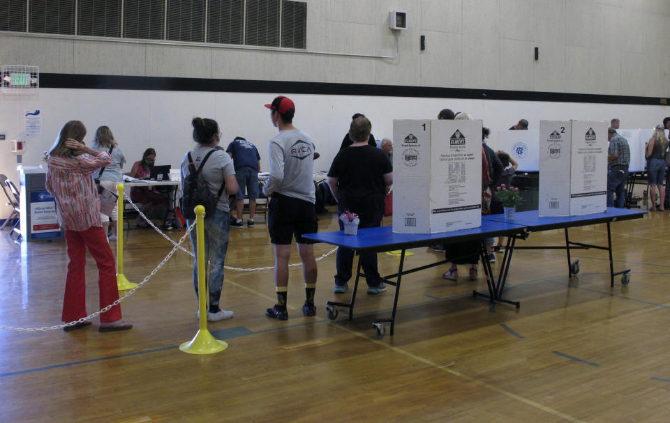 Washoe County voters line up inside a gymnasium at Reed High School in Sparks, Nevada on Tuesday, June 14, 2022, to cast their primary election ballots either by making selections on voting machine computer screens or dropping the ballot that was mailed to them into a ballot drop box if they haven't already returned it in the mail. The spotlight in Nevada was on the GOP primary where Republicans will pick nominees to try to unseat Democratic incumbents in the U.S. Senate and governor's mansion in November. (AP Photo/Scott Sonner).