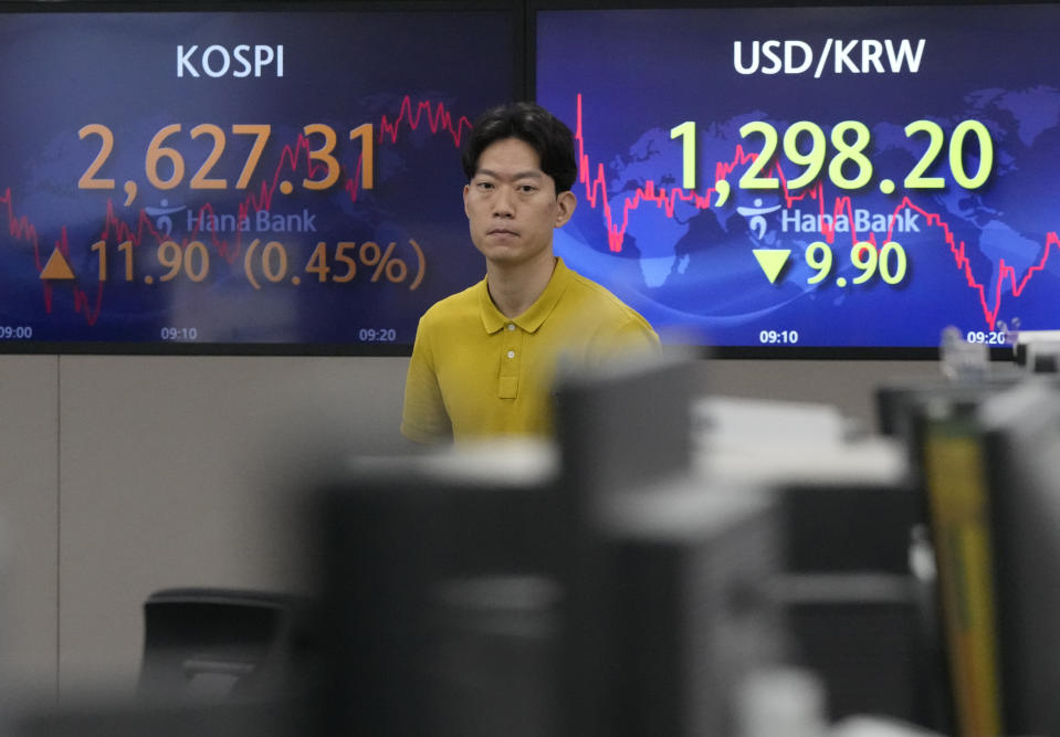 A currency trader walks by screens showing the Korea Composite Stock Price Index (KOSPI), top left, and the foreign exchange rate between U.S. dollar and South Korean won at the foreign exchange dealing room of the KEB Hana Bank headquarters in Seoul, South Korea, Wednesday, June 7, 2023. Asian shares were mixed Wednesday after a day of listless trading on Wall Street in the absence of market-moving data.(AP Photo/Ahn Young-joon)