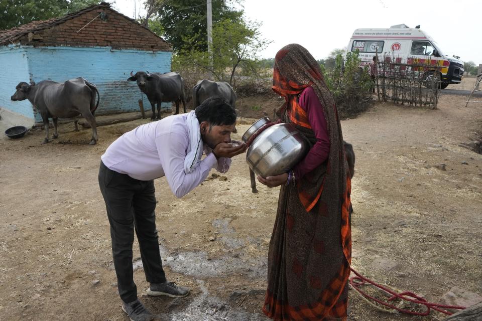 A village woman gives water to Sunil Kumar Naik, an ambulance driver, to quench his thirst during a heat wave, on the way to a hospital, near a village in Banpur in the Indian state of Uttar Pradesh, Saturday, June 17, 2023. The European climate agency calculates that November, for the sixth month in a row, the globe set a new monthly record for heat, adding the hottest autumn to the broken records of record-breaking heat this year. (AP Photo/Rajesh Kumar Singh)